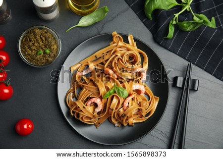 Tasty buckwheat noodles with shrimps served on black table, flat lay