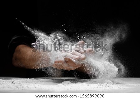 Chef clap white flour dust man hand on black background. Royalty-Free Stock Photo #1565899090