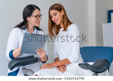 Adult smiling female gynecologist working with patient in modern clinic Royalty-Free Stock Photo #1565916790