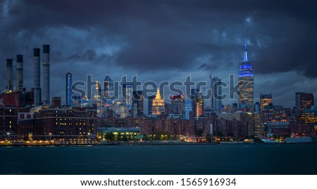 NYC Cityscape with Stormy Cloudy Blue Sky in Background. The Smoke Stacks on the left in the background.