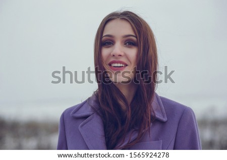 Extremely happy young woman walking outside in the winter time. Copy space for text. Violet coat 