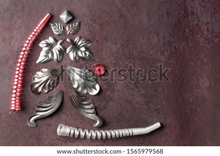 Alternative Christmas tree made of metal, decorative elements in the form of leaves and streamers of white and red on a textured, lilac background. Horizontal layout, copy space, top view.
