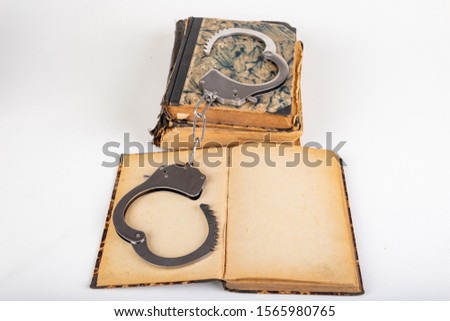 Old books and metal handcuffs. Literature and prison for bad words. Light background.