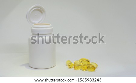 White jar of pills and fish oil pills on white background. White medical containers.