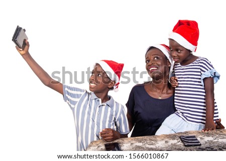 beautiful family wearing a christmas hat and taking picture using a mobile phone while smiling.