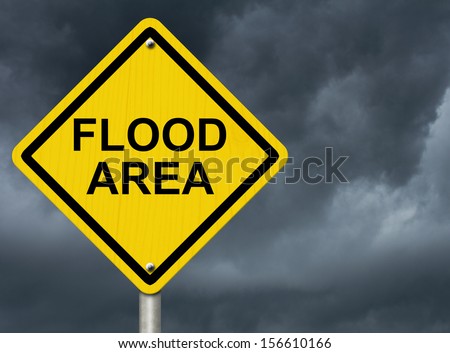 A road warning sign against a stormy sky with words Flood Area, Flood Warning