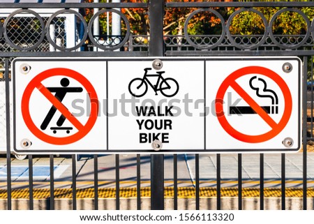 Signs depicting the No Skateboarding, no Smoking and Walk your bike rules posted at a train station