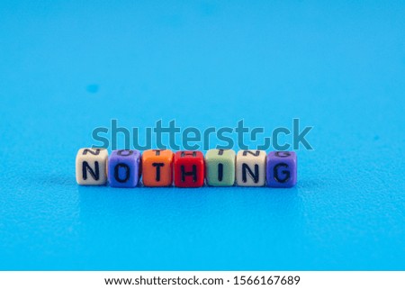 A word NOTHING made by a colourful cube beads alphabet  over blue background.