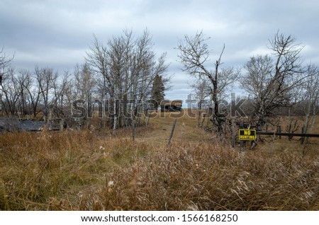 Abandoned wooden shed behind wire fence with the no hunt sign, Alberta farmland. Creepy, scary, haunting concept. Typical canadian countryside. Alberta, Canada
