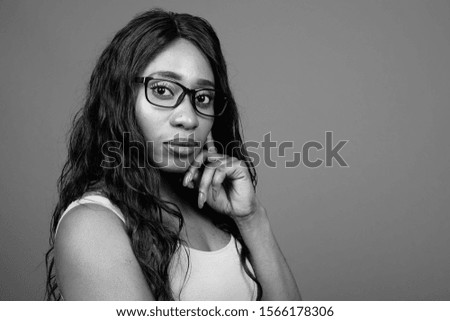 Young beautiful African woman wearing eyeglasses against gray background