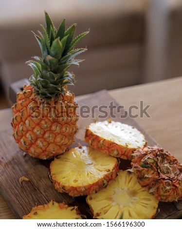 Whole and cut ripe pineapples on wooden table