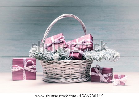 Christmas card with red gift boxes, basket and frosty spruce branches over light wooden background. Old photo stylized image