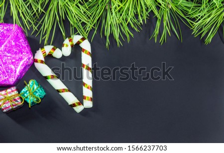 Green twigs from a Christmas tree, with sweets and small gifts on a dark background for the New Year's Eve 2020