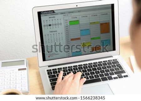 Woman using calendar app on laptop in office, closeup