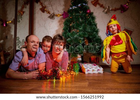 Family consisgitng mother, father and two brothers in carnival costumes at Christmas or new year near the Christmas tree in the room. Mom, dad and boys indoor posing together