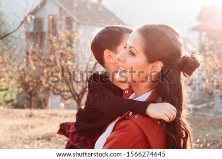 Mom holding her son in her arms. Outdoors photo. Parents kids relationship