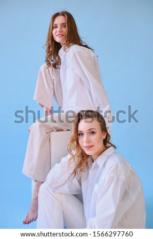 two girls in white clothes pose on a blue background