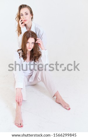 two girls in white clothes on a white background in a photo Studio