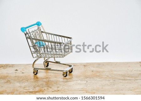 Empty top view mini blue shopping cart  or trolley shopping on wood and white background, concept shopping in supermarket.