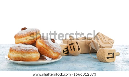 Donuts for Hanukkah, gifts and dreidels on table against white background