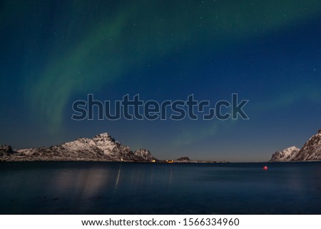 Polar lights, Northern lights, Aurora borealis over fjord mountains with many stars on the sky in the North of Europe , Lofoten islands, Norway, long exposure.