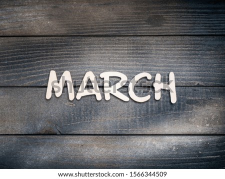 The name of the month is composed of light wooden letters on dark wood. The month of March. 