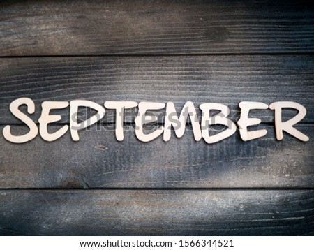 The name of the month is composed of light wooden letters on dark wood. The month of September. 