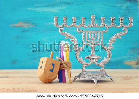 religion image of jewish holiday Hanukkah with menorah (traditional candelabra) and spinning top over wooden table and blue background