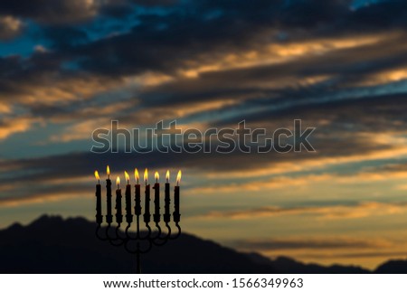 Light of candles are traditional symbol for Hebrew Holidays of Hanukkah. Blurred background with dawn sky, selective focus on candles