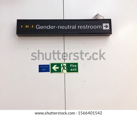A sign says gender neutral restroom and shows the way with an arrow.Image