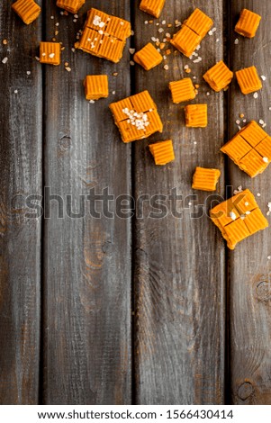 Salted caramel pieces - paradox sweets - on dark wooden background top view frame copy space