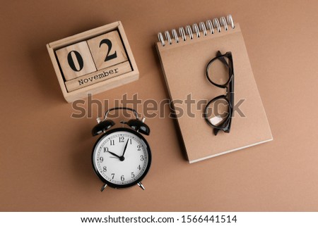 Wooden block calendar, notebook and alarm clock on background, flat lay