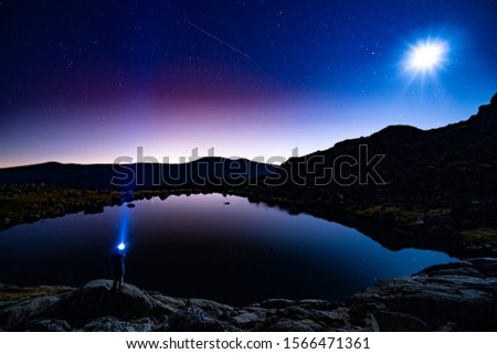 Peñalara lagoon at night with someone looking at night sky Madrid Spain