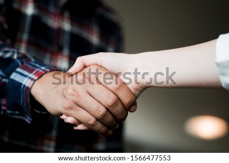Closeup of male and female hands handshaking after effective negotiation showing mutual respect. Two people handshaking expressing respect and trust concept.
