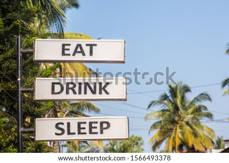 A sign saying "Eat", "Drink" and "Sleep" in a tropical location.