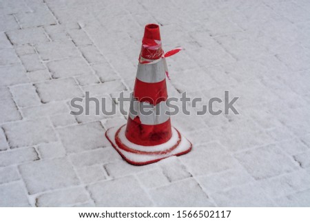 Traffic cone under the snow. Urban, under construction, road work and construction works concept photo.