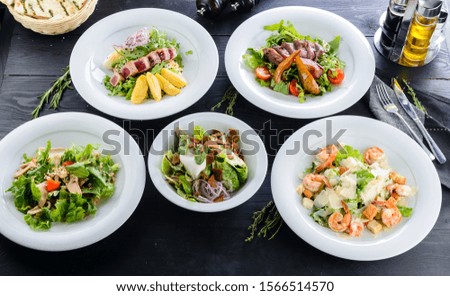 Enjoy your meal. Set of mixed food five plates of salads on a restaurant table to choose from with shrimp, tuna or duck
