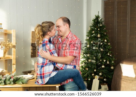 Beautiful happy couple in love cuddles in the Christmas kitchen in the new year 2020