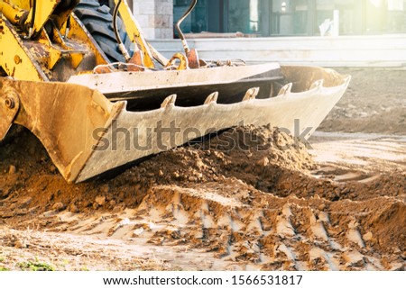 Excavator moving earth with the shovel on the construction site