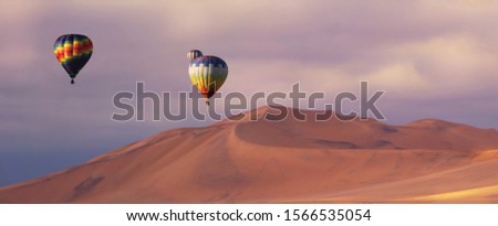 Three colorful hot air balloons over the sand dunes in Namib Desert. Artistic picture. Beauty world.