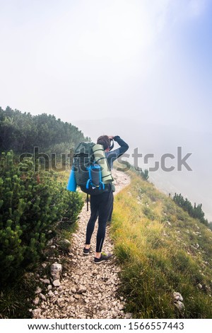 A man in the mountains takes  pictures with his camera. Amazing beauty of hiking, standing on the rocks with backpack.