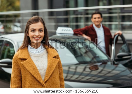 Selective focus of woman smiling at camera and taxi driver at background