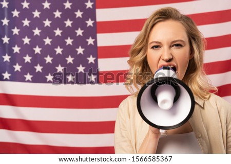 Young woman screaming in loudspeaker with american flag at background