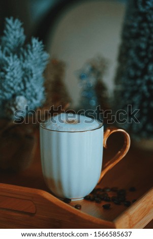 Christmas picture. A cup of flat white coffee, coffee beans. New year tree background.