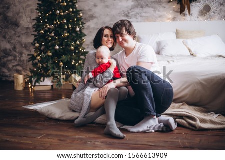 happy family with baby sitting near Christmas tree at home