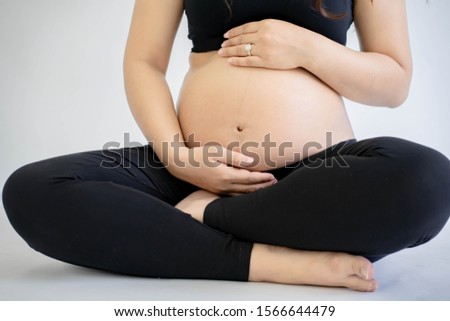 Close up of a beautiful pregnant  woman sit and hugging her tummy.