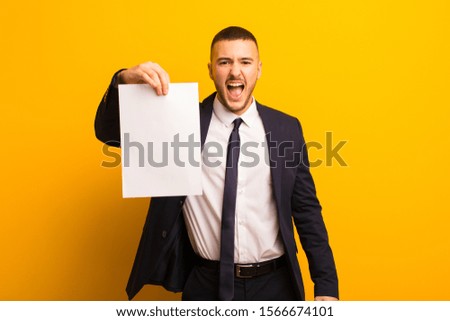 young handsome businessman  against flat background holding an empty piece of paper