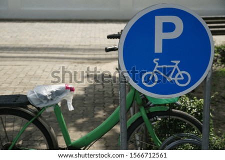 Bicycle parking sign placed on footpath ,a green bicycle parking there in day time , background is footpath.