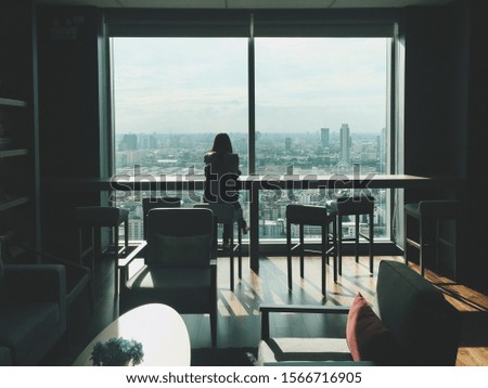 Girl is sitting near window in high building view