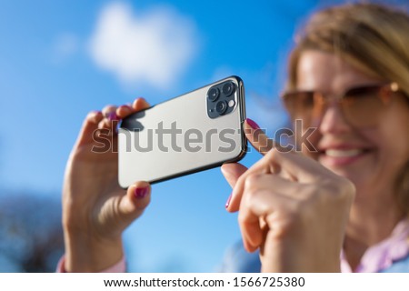 Woman taking photo with modern triple-lens camera phone